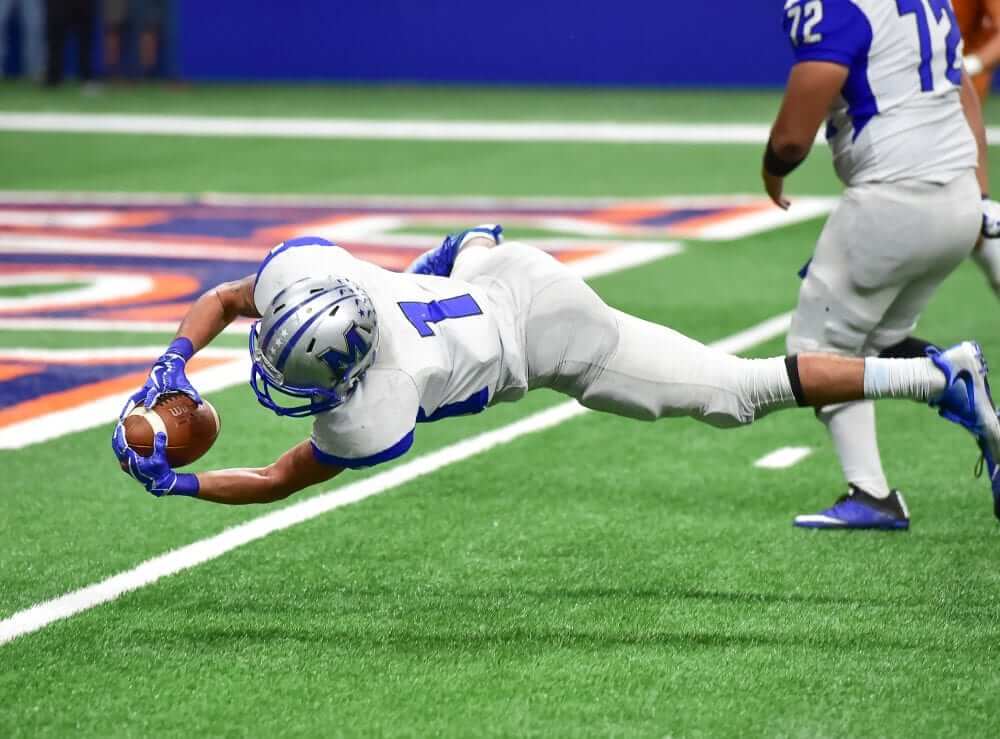 American football athlete catching the ball and falling on the ground