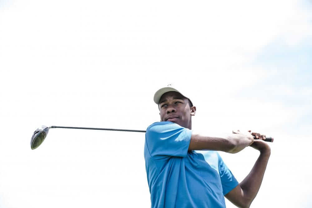 Man wearing a with hat and blue shirt, playing golf