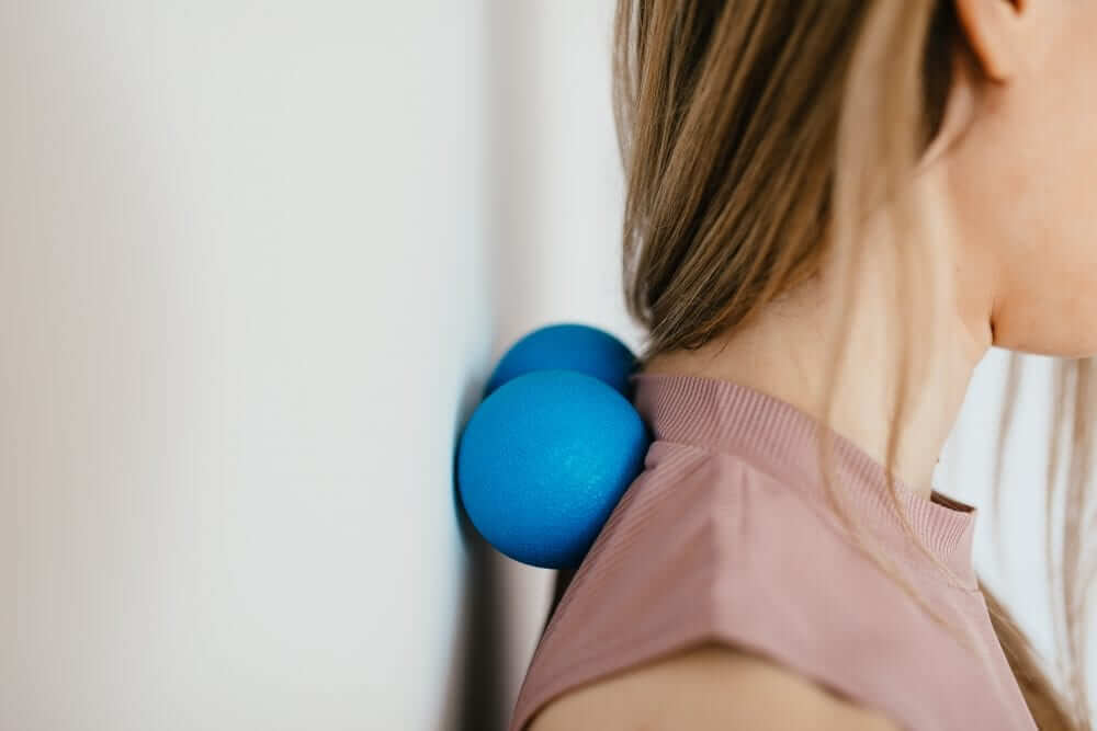 Lady massaging neck with blue wall-mounted balls.