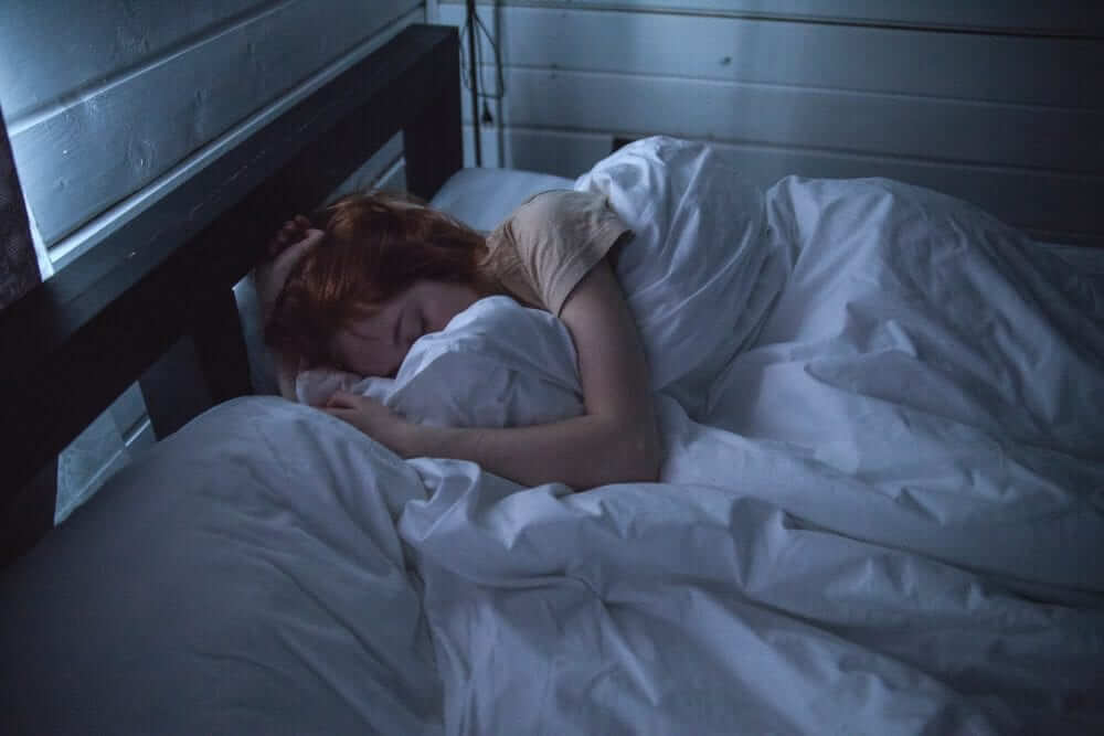Women sleeping in bed, cover by white blankets