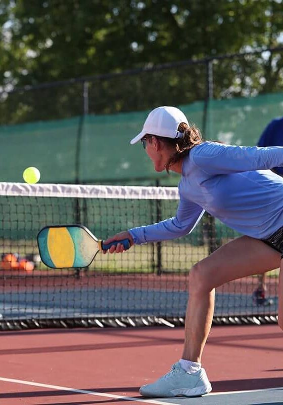 A woman hits a dink shot while playing pickleball.